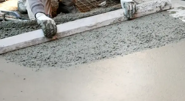 Pracownik wyrównuje świeży beton, przygotowując podłogę garażu. Dobry jaki beton na wylewkę do garażu to klucz do trwałej posadzki.