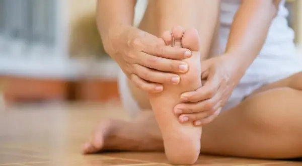 Mani che massaggiano il piede sinistro, alleviando possibili scosse elettriche.