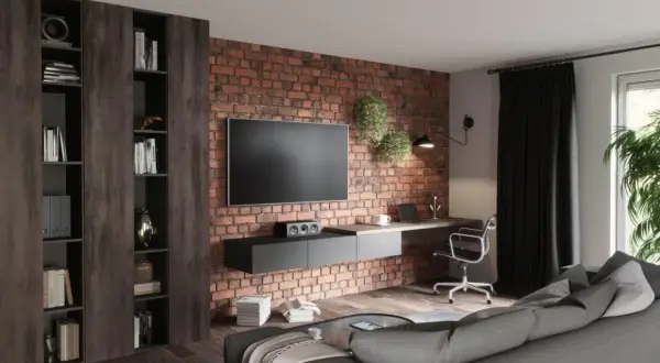 Nowocześnie urządzony salon z ceglaną ścianą, wiszącym TV, biurkiem i wygodną kanapą. Inspiracja, jak urządzić salon nowocześnie.