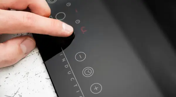 Doigt appuyant sur un bouton de la plaque induction erreur e. L'écran affiche un code d'erreur.