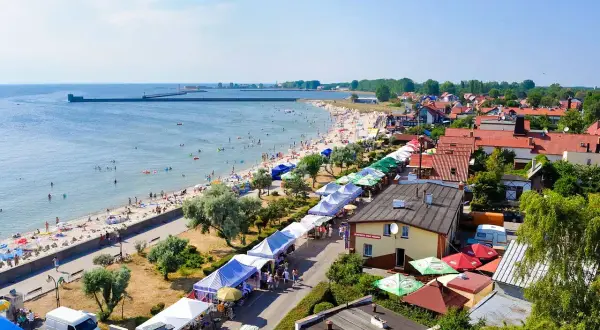 Hel: plaża pełna ludzi, stragany z pamiątkami i jedzeniem, idealne atrakcje dla dzieci.