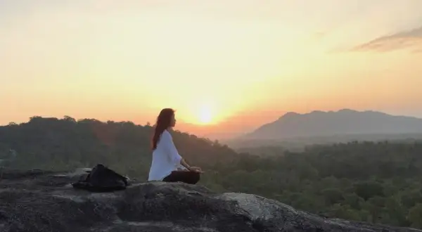 Mujer meditando al amanecer, buscando el equilibrio yin yang en la naturaleza.