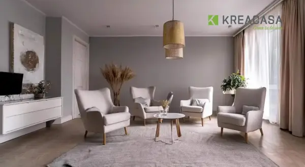 Salotto accogliente con poltrone color ecru, tappeto grigio e un tavolino centrale. Pareti grigie e tende color tortora completano l'arredo.