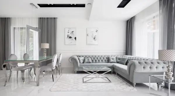 Elegancki salon w stylu nowojorskim z szarą sofą Chesterfield, szklanym stołem i marmurową podłogą.