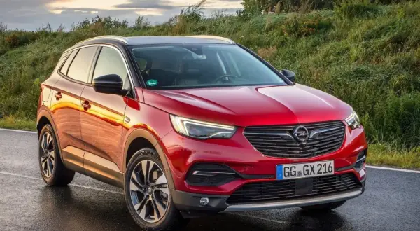 Czerwony Opel Grandland X na mokrej drodze. Wiele pozytywnych opinii o tym modelu.