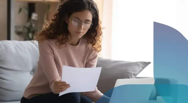 Donna con occhiali legge documenti, lavorando al computer. Scopre che posso intestare le utenze senza avere la residenza.