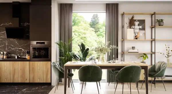 Nowoczesne planowanie kuchni z jadalnią. Drewniane fronty szafek, czarny blat i marmurowa ściana nadają elegancji. Zielone krzesła przy stole tworzą przytulną atmosferę.