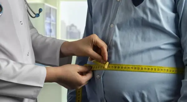 Un médecin mesure le tour de taille d'un homme. Une femme de 50 ans pourrait avoir un tour de taille similaire.