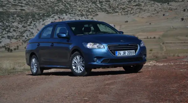 Niebieski Peugeot 301 na tle skalistego, pustynnego krajobrazu.