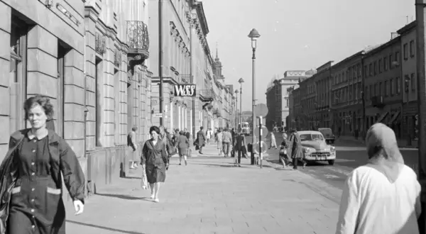 Spacerem po ulicy w nowym świecie, Warszawa. Ludzie idą chodnikiem obok budynków, w tle widać samochody i tramwaj.