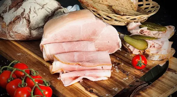 Frisch aufgeschnittener Kochschinken, der Lust macht, ihn selber zu machen. Dazu Brot, Tomaten und Gewürzgurken.