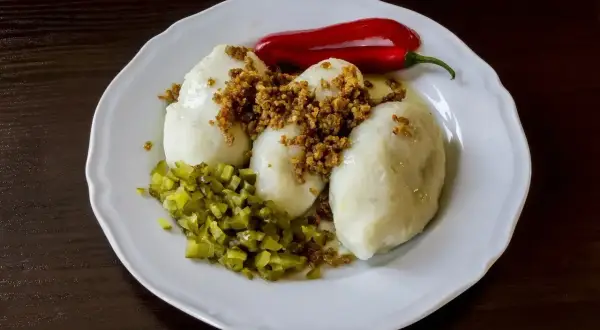 Trzy sycące kartacze z mięsem, posypane skwarkami, z dodatkiem ogórków kiszonych i papryczki chili.
