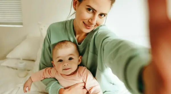Uśmiechnięta mama z dzieckiem na rękach, czuje, kiedy macierzyństwo zaczyna cieszyć.