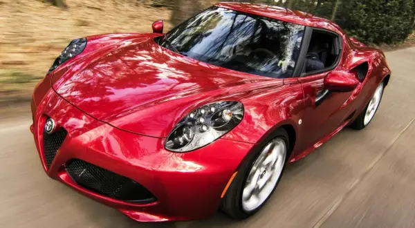 Czerwone Alfa Romeo 4C z połyskiem lakieru perłowy a metalik, pędzące przez las.