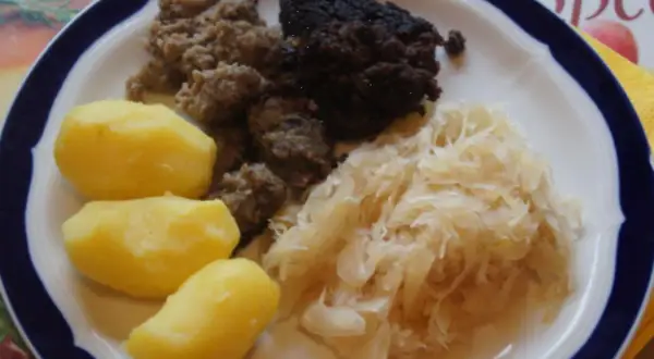 Herzhaftes Gericht: Bratwurst, Blutwurst, Sauerkraut und Salzkartoffeln. Perfekt, um Wellwurst zuzubereiten und zu genießen.