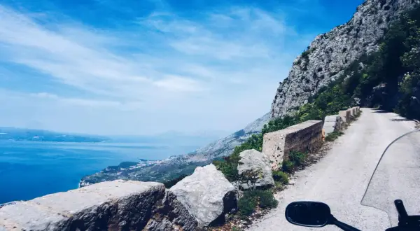 Widok z motocykla na krętą drogę w Chorwacji, z widokiem na morze i góry. Niezapomniana podróż!