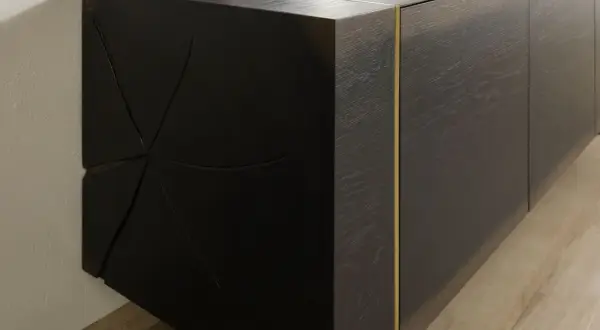 Dunkles Sideboard mit markanter, geometrischer Front. Die Maserung des Holzes und die goldene Leiste unterstreichen, was bedeutet massiv: ein Möbelstück, das Charakter und Beständigkeit ausstrahlt.