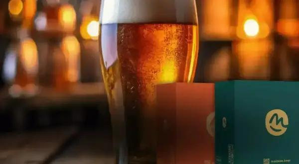 Bicchiere di birra dorata con bollicine, accanto a scatole di birra celiaci.