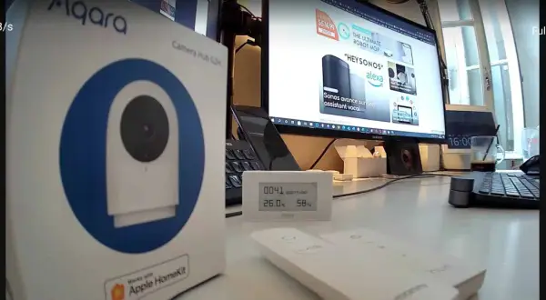 Boîte de l'aqara g2h pro, un hub caméra HomeKit, posée sur un bureau avec un écran d'ordinateur affichant des produits domotiques.