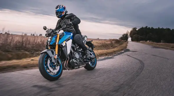 Motocyklista w kasku z brytyjską flagą pokonuje zakręt na drodze, doświadczając zjawiska shimmy.