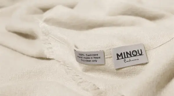 Miękka, kremowa paszmina z metkami: "100% Cashmere, Hand made in Nepal, Dry clean only" i "MINOU Cashmere".