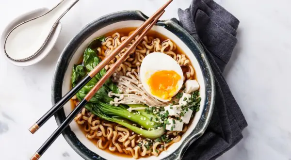 Eine dampfende Schüssel mit köstlicher Ramen-Suppe, garniert mit einem perfekt gekochten Ei, Tofu und Gemüse.