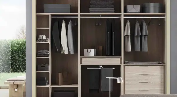 Un armario moderno y funcional, ideal para quienes buscan cómo diseñar un armario con estilo. Ropa colgada, cajones y estantes organizados.