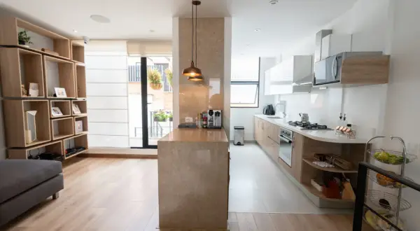 Un tabique de cocina semiabierta al salón crea un espacio moderno y funcional.