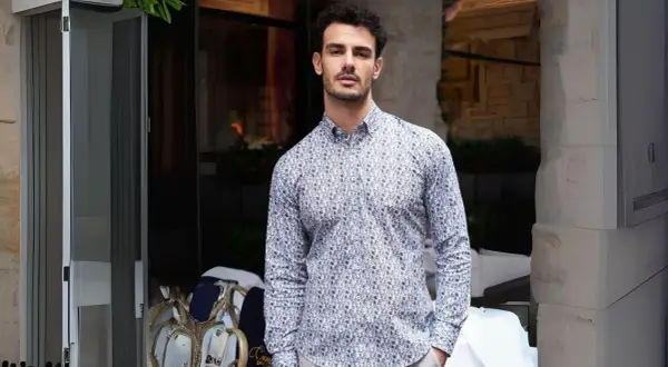 Uomo con camicie di tendenza uomo con fantasia astratta, in piedi all'esterno di un locale.