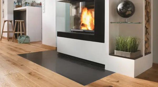 Moderner Kamin mit Sicht auf Flammen, geschützt durch eine Glasplatte. Die Bodenplatte des Ofens entspricht der Vorschrift für Brandschutz.