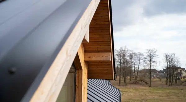 Detalle de cómo hacer un tejado de madera a un agua, con estructura de madera y cubierta metálica oscura.