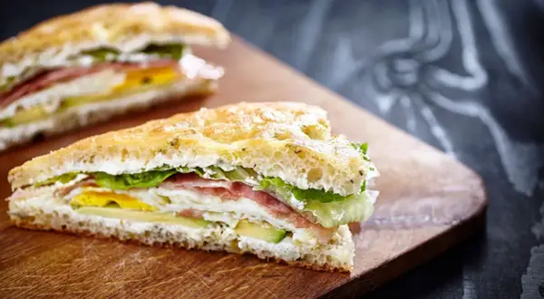 Tramezzini gourmet con prosciutto, uovo, avocado e lattuga su pane soffice. Un'idea per ricette veloci e gustose.