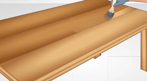Applying a clear coat to a DIY table. The wooden surface is being brushed with a clear finish, enhancing its natural grain.