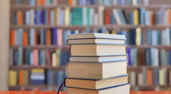 Stos książek na biurku, tło biblioteki z kolorowymi lekturami na e8.