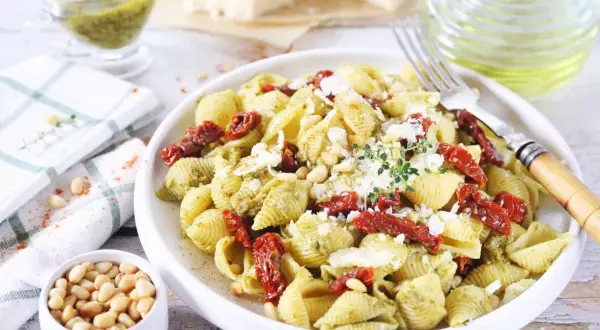 Pyszny makaron z pesto i suszonymi pomidorami, posypany parmezanem i orzeszkami pinii. Idealny na szybki obiad.