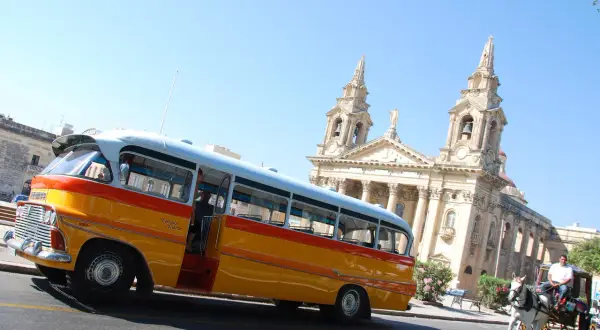 Malta: zabytkowy autobus i dorożka na tle kościoła. Idealne na wycieczkę, kup malta bilety autobusowe!