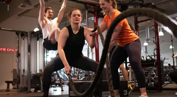 Frauen trainieren mit Seilen, ein Mann hängt an einer Klimmzugstange. Ein Blick in die Praxis der Athletiktrainer Ausbildung.