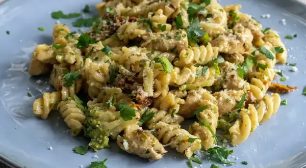 Pyszny makaron z brokułami, kurczakiem i suszonymi pomidorami, posypany parmezanem i natką pietruszki.