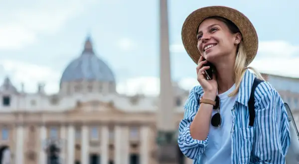 Uśmiechnięta turystka w Rzymie, ciesząca się rozmową przez telefon dzięki internetowi w roamingu.