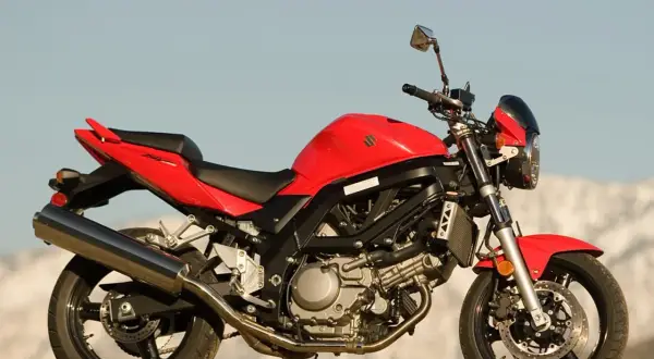 Czerwony motocykl Suzuki SV 650 na tle nieba i gór.