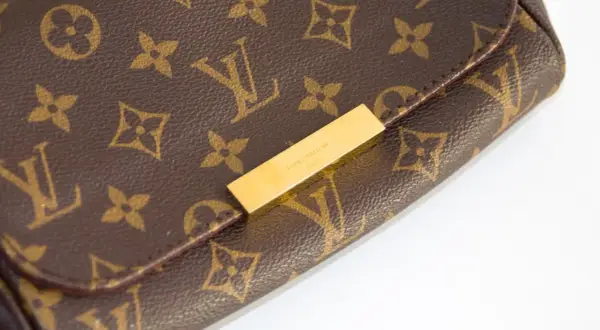 Zbliżenie na brązową torebkę Louis Vuitton z monogramem i złotym zapięciem.