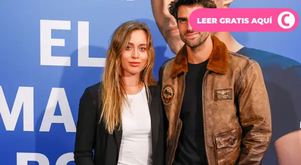 Paula Badosa y su novio posan sonrientes ante un fondo azul con letras blancas.