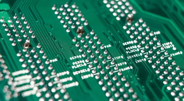 Zielona płyta drukowana z rzędami srebrnych pinów i oznaczeniami, świadectwo roli srebra w elektronice.