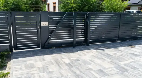 Nowoczesne, czarne ogrodzenie z automatyczną bramą. Czy ogrodzenie można odliczyć od podatku? Pytanie o inwestycję w bezpieczeństwo i estetykę posesji.