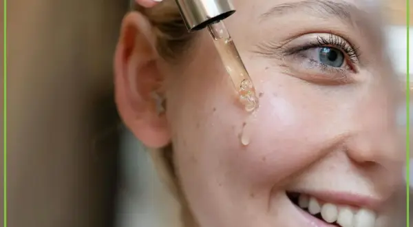 Kropla serum z pipety ląduje na policzku uśmiechniętej kobiety. To może być retinol, który pomaga w pielęgnacji skóry.