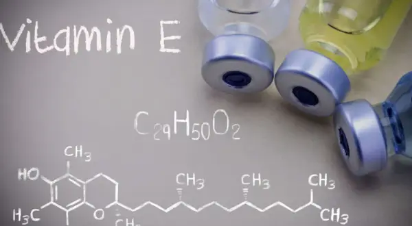 Wizualizacja witaminy E, znanej jako tokoferol, z jej wzorem chemicznym i fiolkami.