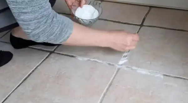 Application d'une pâte de bicarbonate et vinaigre pour nettoyer joint salle de bain.
