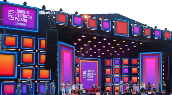 Koncert "Lato z Radiem i Telewizją Polska" w Zakopanem. Kolorowa scena z neonami i ekranami LED, artyści na scenie i tłum widzów.