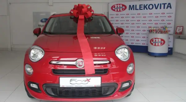 Czerwony Fiat 500X z wielką czerwoną kokardą, gotowy do wręczenia jako nagroda w loterii promocyjnej Vitay.