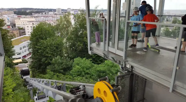 Dzieci z hulajnogami czekają na przejazd kolejką linową Gdynia. Widok na miasto i morze.